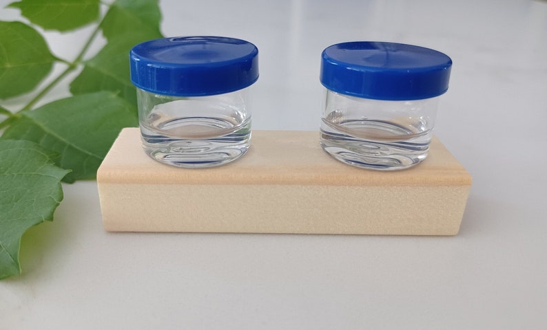 eco eye cases zero waste glass contact lens case eco friendly. Reusable contact lens case. the lid color is dark blue. eco friendly gifts. two glass jars fused together to wood block