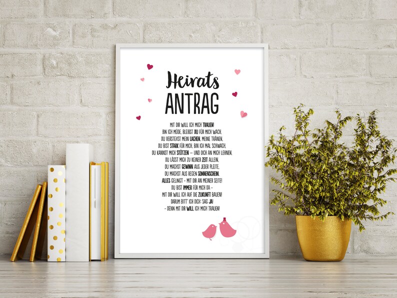 May include: A white framed print with a black and white text design. The text reads "Heirats Antrag" and includes a poem about love and marriage. The print is decorated with pink hearts.
