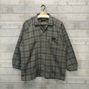 May include: A gray and black plaid long-sleeved button-up shirt with a collared neckline and a single chest pocket.