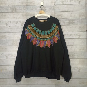 May include: Black sweatshirt with a colorful geometric design around the neckline. The design features teal, gold, purple, and red accents.