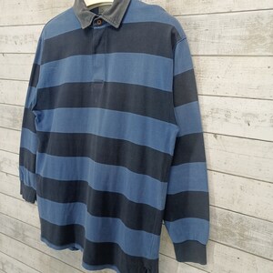 May include: A blue and black striped long-sleeve rugby shirt with a collared neckline and a button closure.