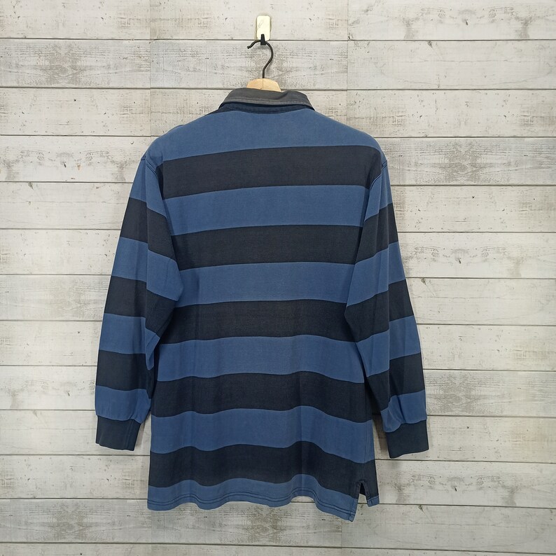 May include: A blue and black striped long-sleeve shirt with a collared neckline.