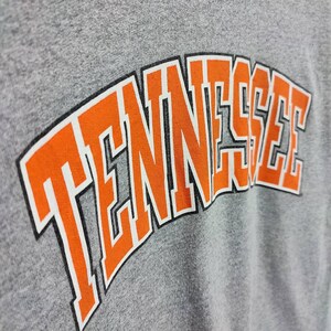 May include: A gray t-shirt with the word "TENNESSEE" printed in orange letters with a black outline.