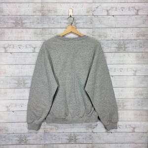 May include: A gray sweatshirt with long sleeves and a crew neck.