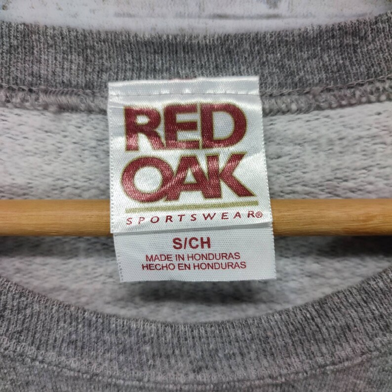 May include: A gray sweatshirt with a white tag that reads "Red Oak Sportswear" and "S/CH Made in Honduras Hecho en Honduras".