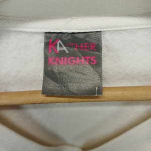 May include: White tag with black and pink text that reads "KA for HER KNIGHTS APPAREL 2XL 22/26 18W 20W MADE IN CHINA HECHO EN CHINA"