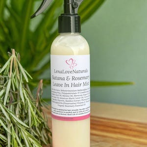 May include: A clear spray bottle with a black nozzle labeled "OFF" contains a light yellow liquid. The label reads "LenaLoveNaturals Batana & Rosemary Leave In Hair Mist." Rosemary sprigs are in the foreground.