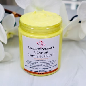May include: A yellow jar of turmeric butter labeled "LenaLoveNaturals Glow up Turmeric Butter" with the tagline "Handmade with Love". The jar is sitting on a white surface with white flowers in the background.