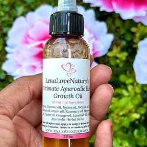 Puede incluir: Una botella de vidrio transparente con una tapa negra y una etiqueta que dice "LenaLove Naturals Ultimate Ayurvedic Hair Growth Oil". La etiqueta enumera todos los ingredientes naturales, incluyendo aceite de coco, aceite de jojoba, aceite de aguacate, aceite de arg&aacute;n, aceite de romero, aceite de pimienta, aceite de ricino, fenogreco, aceite de lavanda, y m&aacute;s. La botella est&aacute; llena de un l&iacute;quido &aacute;mbar claro y est&aacute; sentada en una mano. La botella es de 2 fl oz.