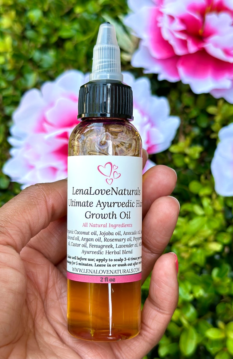 Puede incluir: Una botella de vidrio transparente con una tapa negra y una etiqueta que dice "LenaLove Naturals Ultimate Ayurvedic Hair Growth Oil". La etiqueta enumera todos los ingredientes naturales, incluyendo aceite de coco, aceite de jojoba, aceite de aguacate, aceite de arg&aacute;n, aceite de romero, aceite de pimienta, aceite de ricino, fenogreco, aceite de lavanda, y m&aacute;s. La botella est&aacute; llena de un l&iacute;quido &aacute;mbar claro y est&aacute; sentada en una mano. La botella es de 2 fl oz.