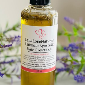 May include: A clear glass bottle with a black cap and a pink label that reads "Lena Love Naturals Ultimate Ayurvedic Hair Growth Oil". The label lists all natural ingredients and instructions for use. The bottle is sitting on a white surface with purple flowers in the background.