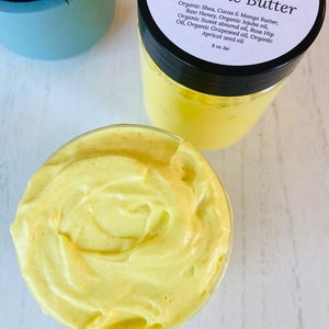 May include: A glass jar filled with a yellow turmeric butter. The jar has a black lid and a white label that reads "LenaLoveNaturals Glow up Turmeric Butter" and lists the ingredients: Organic Shea, Cocoa & Mango Butter, Raw Honey, Organic Jojoba oil, Organic Sweet almond oil, Rose Hip Oil, Organic Grapeseed oil, Organic Apricot seed oil. The label also states "8 oz Jar".