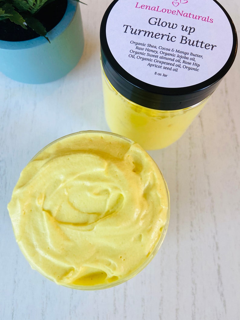 May include: A glass jar filled with a yellow turmeric butter. The jar has a black lid and a white label that reads "LenaLoveNaturals Glow up Turmeric Butter" and lists the ingredients: Organic Shea, Cocoa & Mango Butter, Raw Honey, Organic Jojoba oil, Organic Sweet almond oil, Rose Hip Oil, Organic Grapeseed oil, Organic Apricot seed oil. The label also states "8 oz Jar".