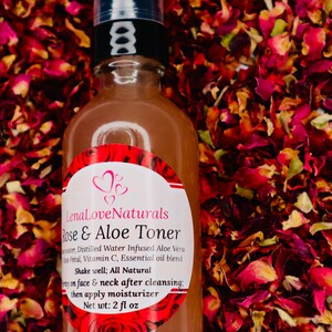May include: A brown glass bottle with a black pump top and a white label that reads "Lena Love Naturals Rose & Aloe Toner". The label also includes the ingredients: "Distilled Water Infused Aloe Vera Rose Petal, Vitamin C, Essential oil blend". The bottle is sitting on a bed of dried rose petals.