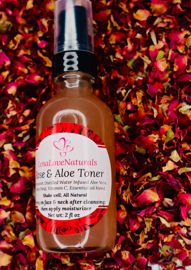 May include: A brown glass bottle with a black pump top and a white label that reads "Lena Love Naturals Rose & Aloe Toner". The label also includes the ingredients: "Distilled Water Infused Aloe Vera Rose Petal, Vitamin C, Essential oil blend". The bottle is sitting on a bed of dried rose petals.