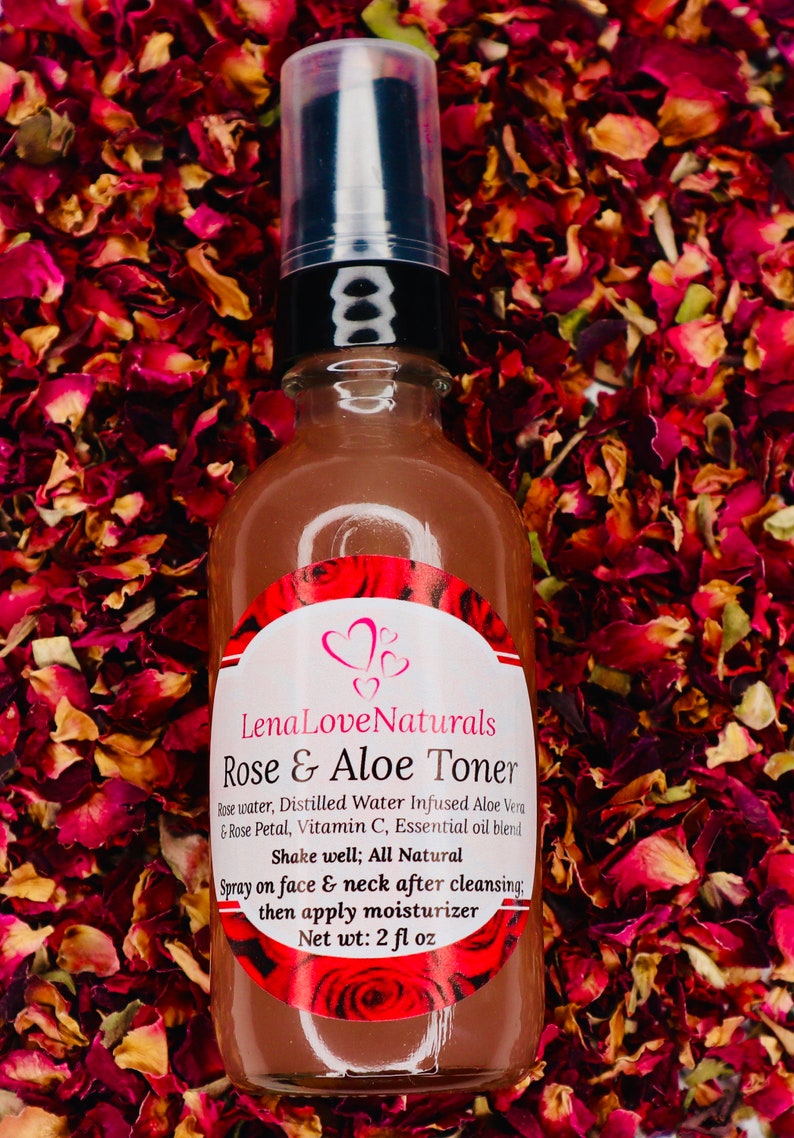 May include: A brown glass bottle with a black pump top and a white label that reads "Lena Love Naturals Rose & Aloe Toner". The bottle is surrounded by rose petals.