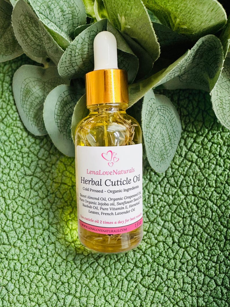 May include: A clear glass bottle of Lena Love Naturals Herbal Cuticle Oil with a gold cap and white dropper. The label lists ingredients like Sweet Almond Oil and French Lavender Oil. The bottle is 1 fl oz.