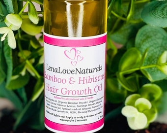 Puede incluir: Una botella de 4 fl oz de aceite para el crecimiento del cabello de bambú e hibisco Lena Love Naturals. La botella es de vidrio transparente con una tapa negra y un gotero. La etiqueta es rosa con texto blanco y presenta dos corazones. La botella está sobre un lecho de flores de hibisco secas.