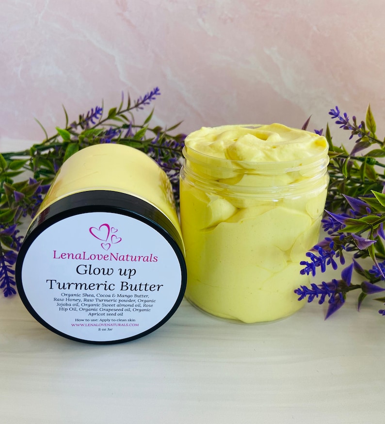 May include: A glass jar filled with a yellow turmeric butter. The jar has a black lid and a white label that reads "LenaLoveNaturals Glow up Turmeric Butter". The label lists the ingredients, instructions for use, and the website address.