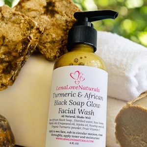 May include: A 4-ounce bottle of Lena Love Naturals Turmeric & African Black Soap Glow Facial Wash. The bottle is clear and has a yellow liquid inside. The label is white with black text and pink hearts. The bottle is sitting on a white surface with a brown bar of soap in the background.