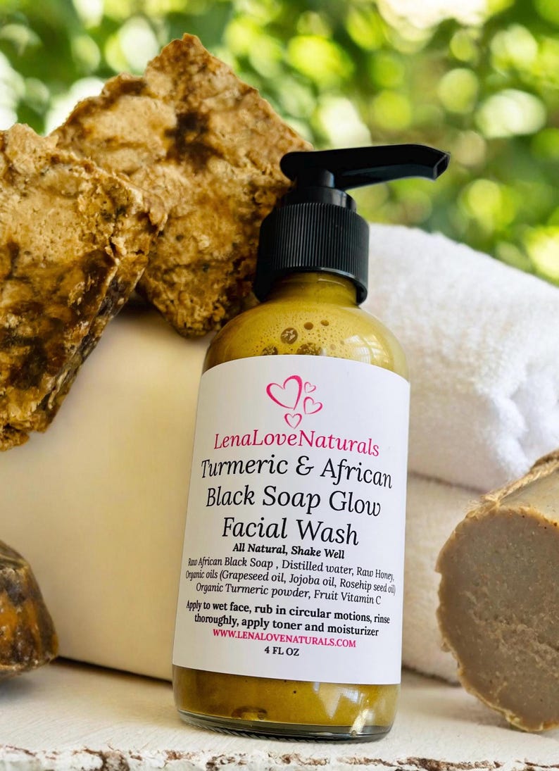 May include: A 4-ounce bottle of Lena Love Naturals Turmeric & African Black Soap Glow Facial Wash. The bottle is clear and has a yellow liquid inside. The label is white with black text and pink hearts. The bottle is sitting on a white surface with a brown bar of soap in the background.