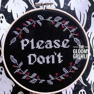 May include: Black embroidery hoop with white text that reads "Please Don't" surrounded by a wreath of red berries and gray leaves. The text "The Gloomy Gremlin" is in the bottom right corner.