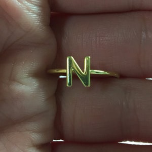 May include: Gold initial ring with the letter N.