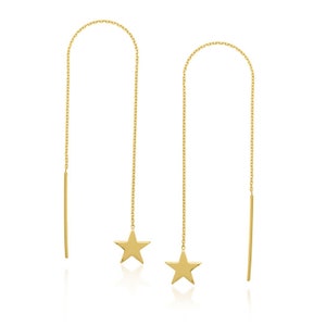 May include: A pair of gold-colored threader earrings. Each earring features a delicate chain that arches over and dangles down, with a star charm at the bottom. A straight bar hangs from the top of the chain.