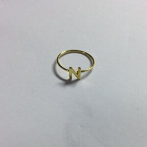 May include: A gold-colored ring with the letter N on it.