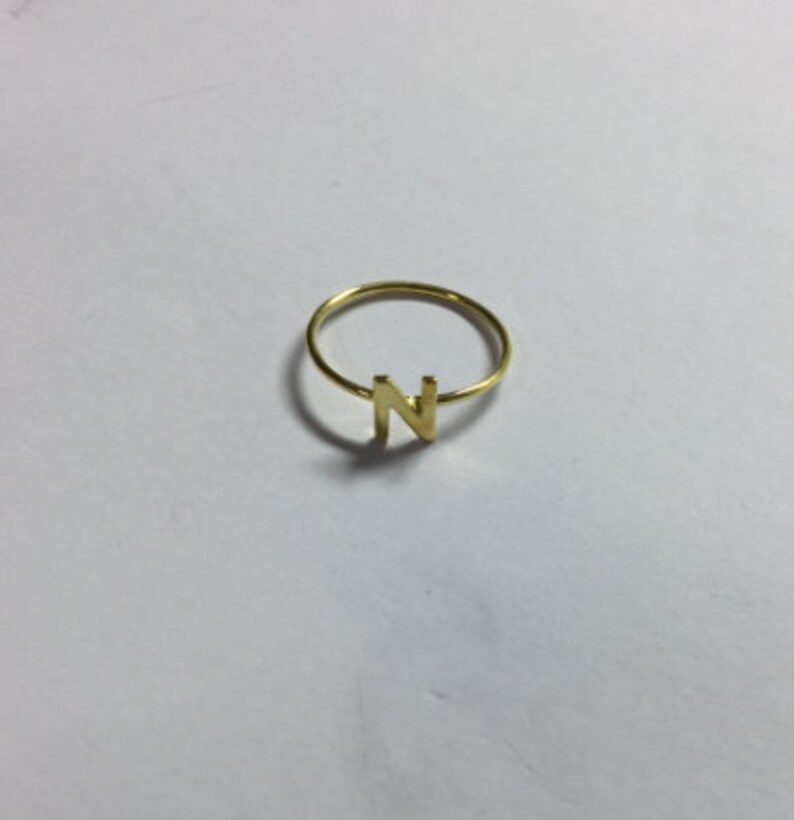May include: A gold-colored ring with the letter N on it.