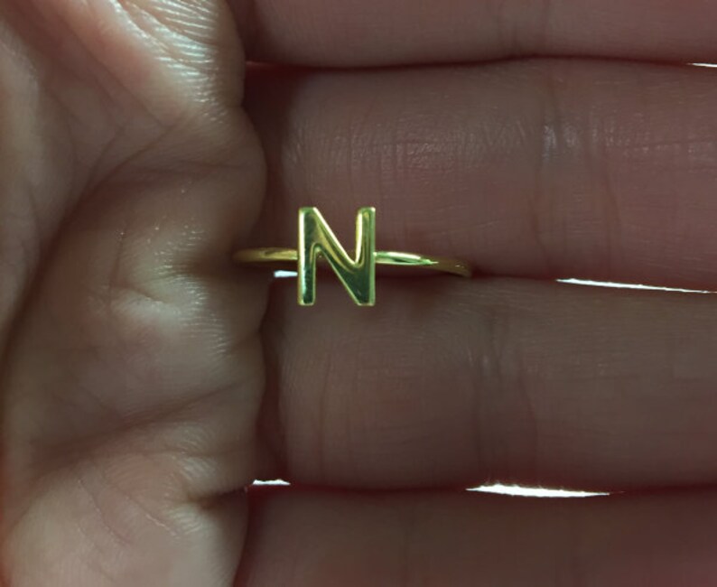 May include: Gold initial ring with the letter N.