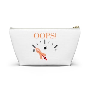 May include: White canvas makeup bag with a black and orange gas gauge graphic. The gauge is empty and the needle is pointing to the "E" for empty. The text "OOPS!" is printed above the gauge.
