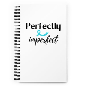 May include: White spiral-bound notebook with the words "Perfectly imperfect" in black script and a light blue ribbon graphic. The notebook has a black spiral binding along the left edge.