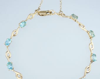 May include: A gold bracelet with a delicate chain and oval-shaped blue gemstones. The bracelet has a clasp closure.