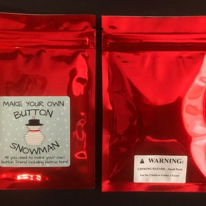 May include: Red zippered pouch with a white label that says "Make Your Own Button Snowman. All you need to make your own button friend including instructions!" and a warning label that says "WARNING: CHOKING HAZARD - Small Parts. Not for Children Under 3 Years."