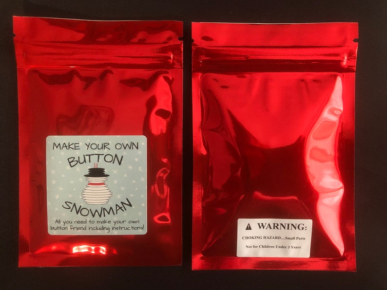 May include: Red zippered pouch with a white label that says "Make Your Own Button Snowman. All you need to make your own button friend including instructions!" and a warning label that says "WARNING: CHOKING HAZARD - Small Parts. Not for Children Under 3 Years."
