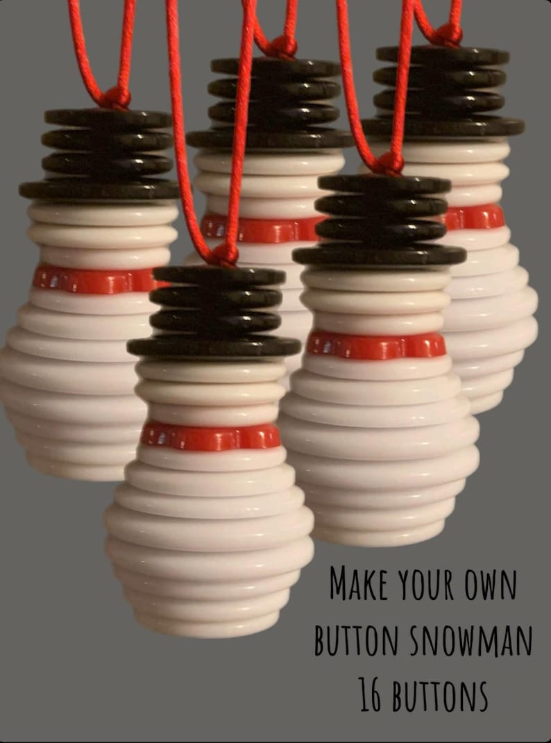 May include: Four white button snowmen ornaments with red and black buttons. The snowmen are hanging from red string. The text "MAKE YOUR OWN BUTTON SNOWMAN 16 BUTTONS" is at the bottom of the image.