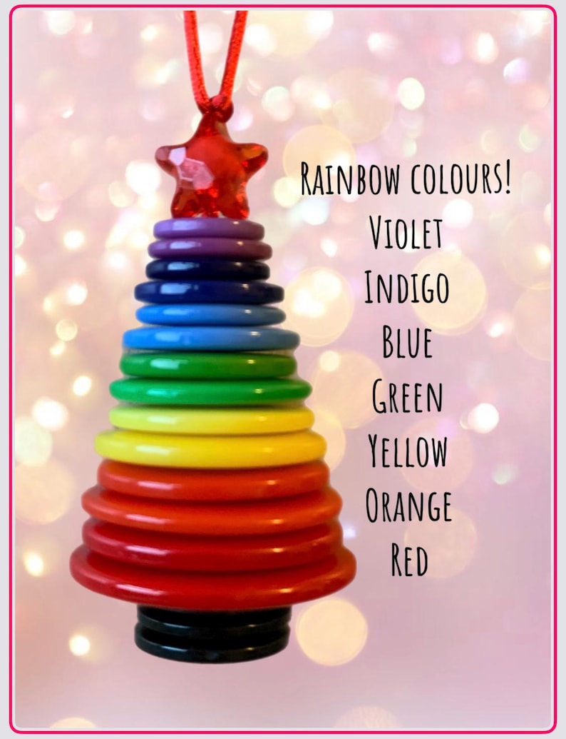 May include: A rainbow-colored Christmas tree ornament made of stacked plastic rings. The ornament is hung from a red string and has a star-shaped topper. The colors of the rings are red, orange, yellow, green, blue, indigo, and violet. The text "RAINBOW COLOURS!" is written above the ornament, followed by the colors of the rings in descending order.