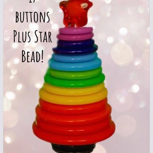 May include: 17 colorful buttons stacked in a rainbow pattern to form a Christmas tree shape, with a red star bead at the top. The text "MAKE YOUR OWN RAINBOW TREE" is at the bottom of the image.