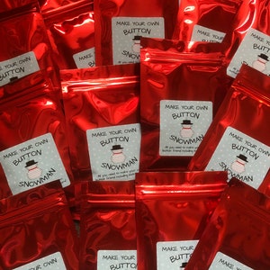 May include: Multiple red zippered bags with white labels that say "Make Your Own Button Snowman". The labels have a snowman illustration and instructions on how to make a button snowman.