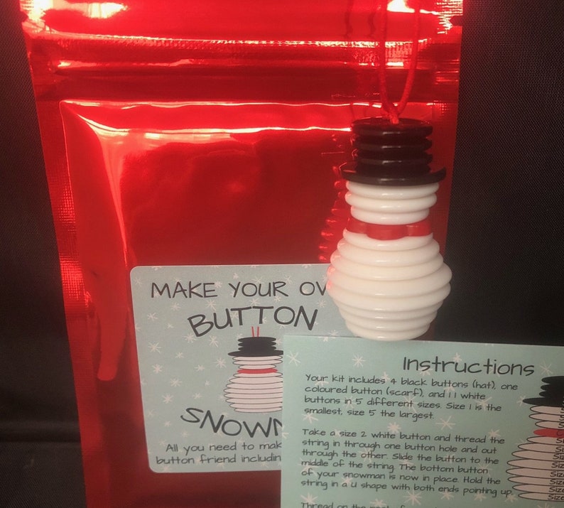 May include: A craft kit to make a snowman out of buttons. The kit includes white buttons, black buttons, a red button, and a brown button. The instructions say "Make your own button snowman".