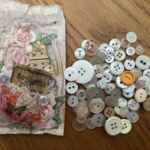 Puede incluir: Una tarjeta de estilo vintage con un diseño floral, notas musicales y la palabra "Enciclopedia". La tarjeta está rodeada de una variedad de botones blancos, marrones y transparentes.
