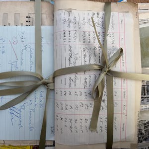Può includere: Una raccolta di carte d'epoca, tra cui appunti manoscritti, pagine di registro e spartiti, legate insieme con un nastro verde chiaro. Le carte hanno pagine ingiallite e il nastro è legato con un fiocco decorativo.