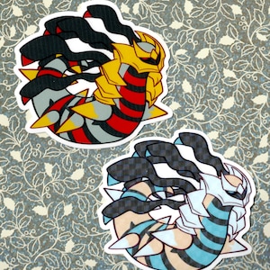 Pode incluir: Dois adesivos de Pokemon, um com um design vermelho, preto e amarelo e o outro com um design azul, preto e branco.