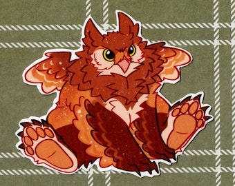 May include: A brown and orange cartoon owl with large, round eyes and a wide, open beak. The owl has fluffy feathers and a small, round body. It is sitting on a green and white plaid background.