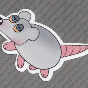 May include: A gray and pink cartoon mouse with large blue eyes and a pink tail. The mouse is looking up and has a surprised expression.