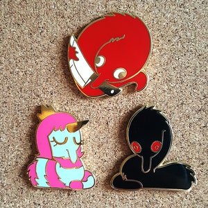 May include: Four enamel pins featuring cartoon characters. The first pin is red and features a character with a knife. The second pin is pink and blue and features a character with a crown. The third pin is black and features a character with red eyes. The fourth pin is black and features a character with red eyes.