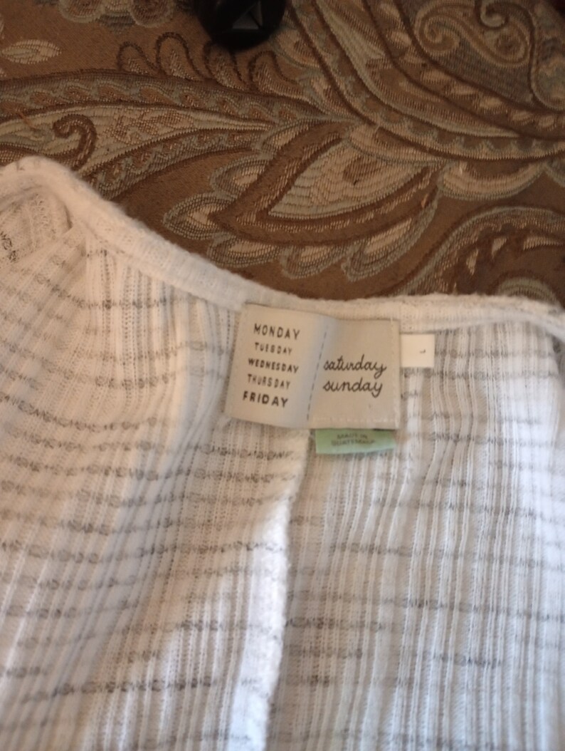 May include: White ribbed knit top with a white tag that says "Monday, Tuesday, Wednesday, Thursday, Friday, Saturday, Sunday".