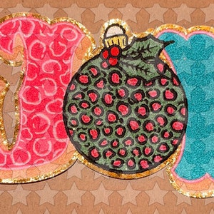 May include: A festive, glittery, pink, blue, and green "JOY" sign with a stylized ornament in the center.