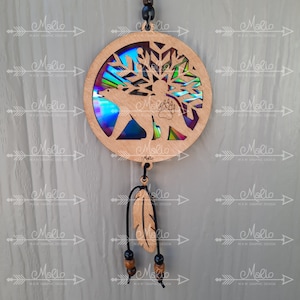 May include: A wooden dreamcatcher with a polar bear silhouette and a snowflake design. The dreamcatcher has a iridescent background and a brown feather hanging from it.